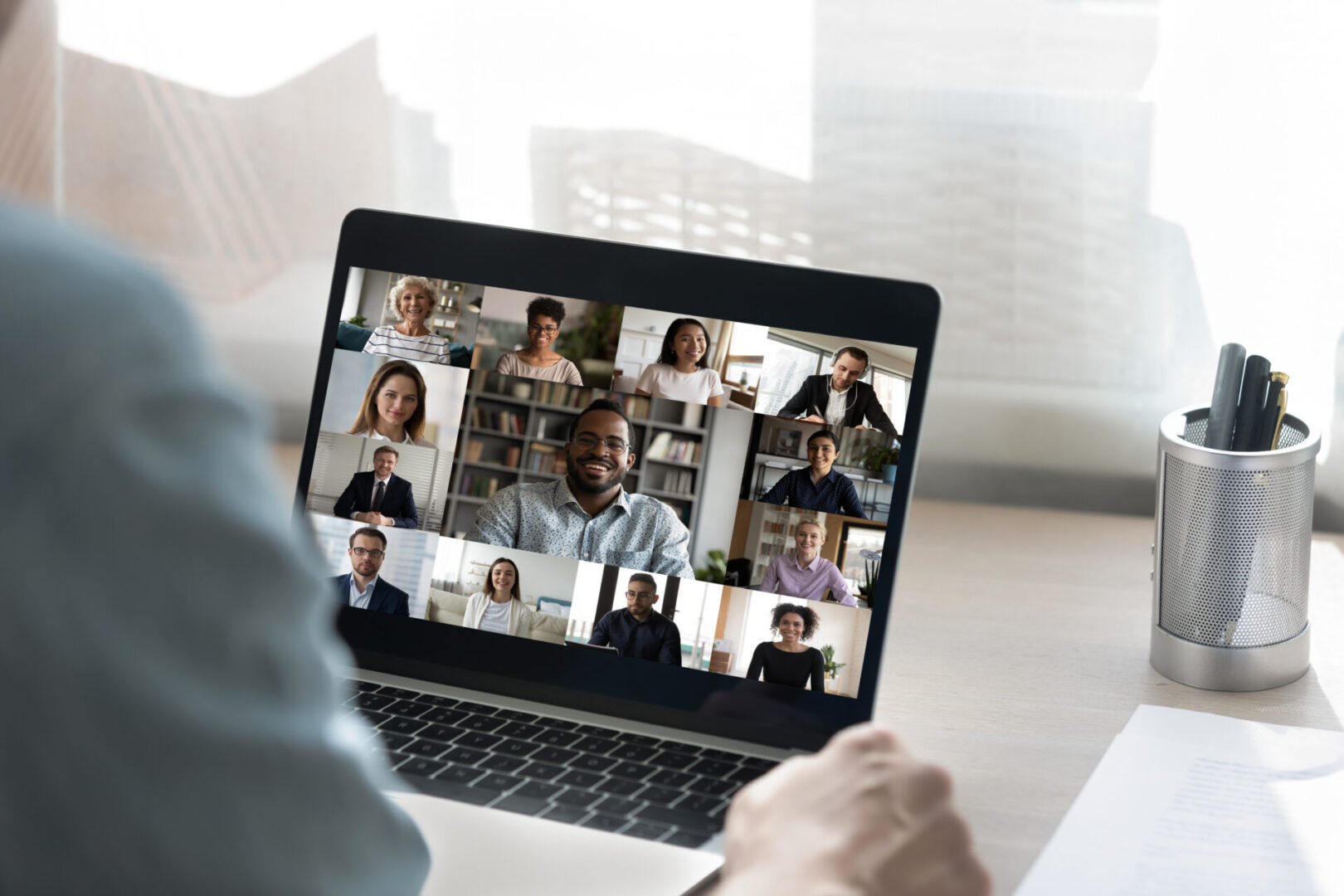 Back view of male employee have online video call on laptop with diverse multiethnic colleagues, man worker involved in webcam conference or virtual event on computer with multiracial businesspeople